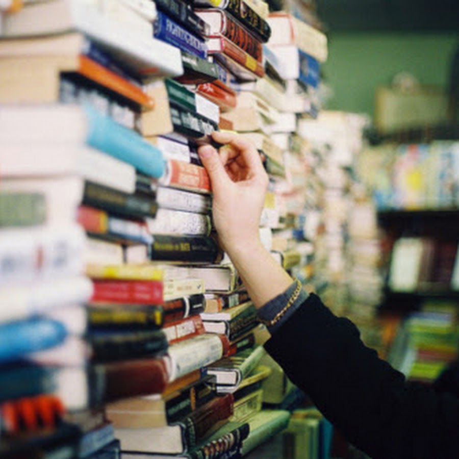 фотосессия в библиотеке. рука достает книгу с полки. арендовать книгу. человек берет книгу с полки. книжный бизнес.